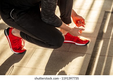 Athlete sprinter getting ready to run tying shoe laces while sitting on race track on stadium