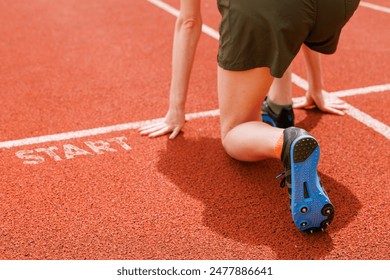 An athlete at the start line, poised for a sprint, concentrating on their lower body and the track surface below - Powered by Shutterstock