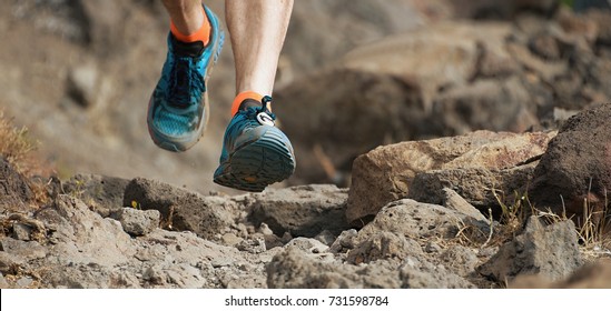 Athlete Trail Running In The Mountains On Rocky Terrain, Sports Shoes Detail