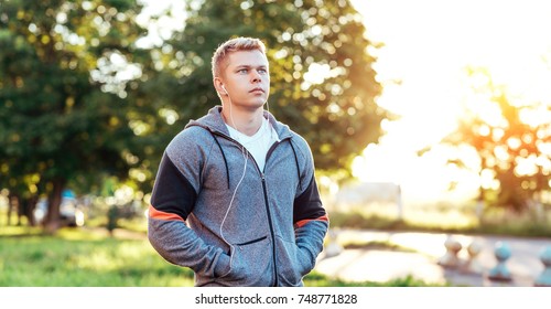 Athlete Trainer In Headphones Listens To An Audiobook, Confident Look. Summer Lifestyle, Motivation Is Strong. Outdoors Park.