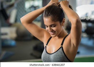 Athlete tying hair before her workout at gym. Young woman is getting ready for fitness training. Sportsgirl adjusting pony tale before training. - Powered by Shutterstock