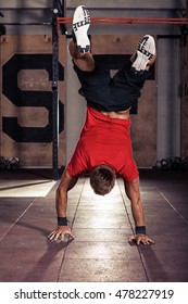 Athlete walking on his hands standing upside down in gym