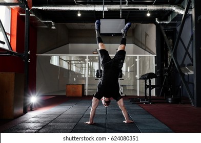 Athlete walking on his hands standing upside down in gym. Man doing push ups on his hands. Crossfit training. Workout lifestyle concept.  Full body length portrait