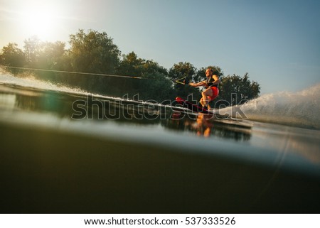 Athlete water skiing behind a boat. Man wakeboarding on a lake.