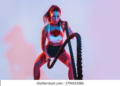 Athlete waving the ropes as part of fat burning workout in fitness studio. Woman exercising with battling ropes at the gym - Shutterstock ID 1794314386