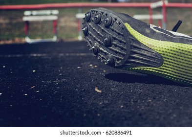 Athlete Wearing Spikes For Track Meet With Hurdles In The Background. Great Sports Graphic For Athletics Or Running Program.