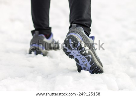 Athlete woman jogging feet on snow at morning training. Sport background