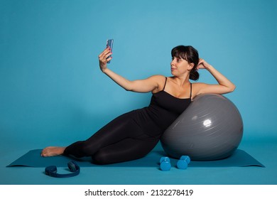 Athlete Woman Leaning On Yoga Fitball Taking Photo Using Smarphone Putting On Social Media. Personal Trainer Practicing Yoga Exercise Stretching Body Muscles Working At Healthy Lifestyle