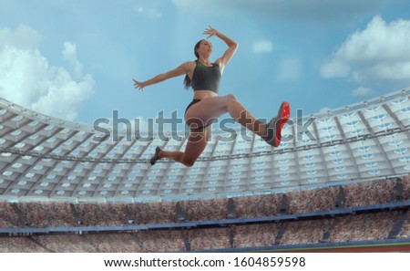 Athlete woman makes a long jump at the sports championship.