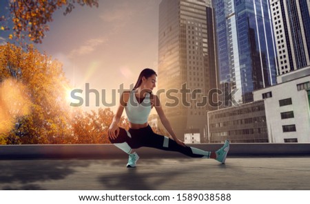 Athlete woman on the city street. Sport tight clothes. Bright sunset, city background. Horizontal.