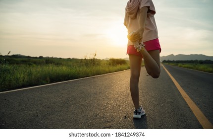 athlete woman runner stretching leg and feet and preparing for trail running on a Countryside Road at Sunrise.Active,Jogging workout and sport healthy lifestyle concept. - Shutterstock ID 1841249374