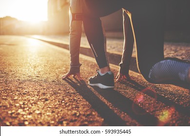 Athlete woman in running start pose on the city street. Sport tight clothes. Bright sunset, blurry background. Horizontal - Shutterstock ID 593935445