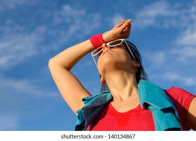 Athlete Woman Wiping The Sweat From His Brow With A Wristband. Tired Fitness Caucasian Girl Sweating After Exercising On Summer Outdoor.