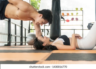 Athlete young couple strong happy workout together in gym. Handsome man strength with his girlfriend sporty slim fit lying on the floor at fitness. Lifestyle sport wellness concept.