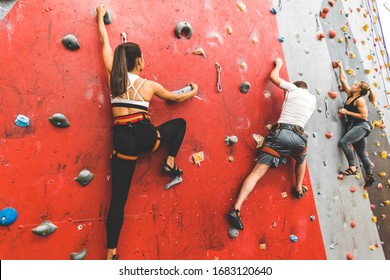 Athletes Climber Moving Up On Steep Rock, Climbing On Artificial Wall Indoors. Extreme Sports And Bouldering Concept