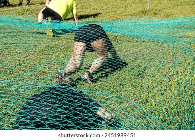 athletes crawling under a net at an obstacle course race, ocr race - Powered by Shutterstock