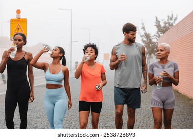 Athletes hydrating after workout in city, showing dedication to fitness. Urban setting adds dynamic backdrop to active lifestyle. Candid moment captures strength and progress in fitness goals - Powered by Shutterstock