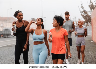 Athletes hydrating in city after workout, showcasing healthy habits and togetherness in active lifestyle. Cityscape adds cool vibe to cool down session - Powered by Shutterstock