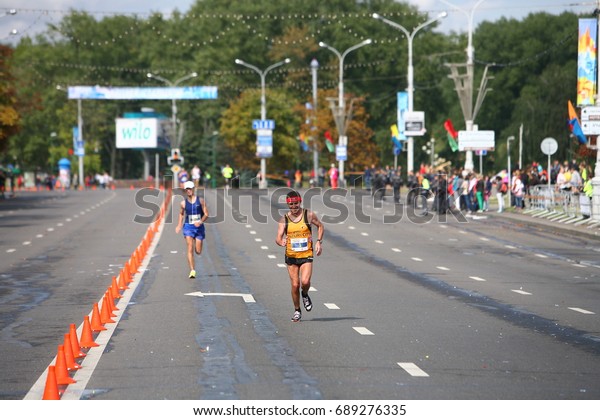 Athletes lovers during the run over the annual Minsk\
Autumn Half Marathon on the road divided by cones.Belarus, Minsk,\
September 2015