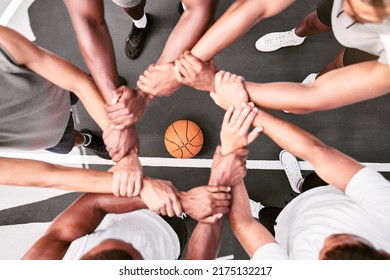 Athletes showing trust and standing united. Men expressing team spirit with their hands joined huddling at a basketball game. Sportsmen holding wrists in huddle for support and unity at sports match.