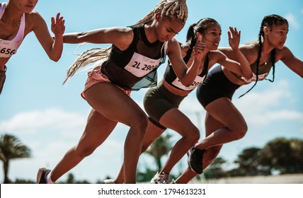 Athletes starting off for a race on a running track. Female runner starting a sprint at stadium track. - Shutterstock ID 1794613231