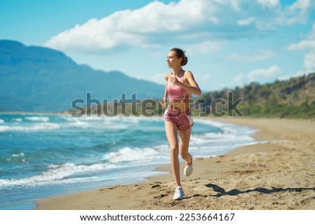 Athletic active runner jogging outdoors on beautiful tropical seashore with mountains view. Running woman healthy lifestyle