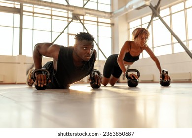 athletic african american couple in sports uniforms train and do push-ups in the gym, man trainer and woman go in for sports in the fitness room in the morning