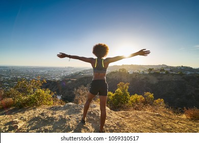 athletic african american woman celebrating reaching top of runyon canyon with arms open - Powered by Shutterstock