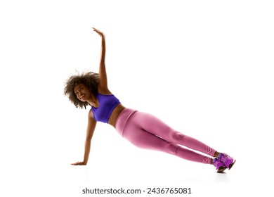 Athletic African-American woman in purple activewear balancing, training against white studio background. Concept of sport, mourning routine, active and healthy lifestyle, energy, action.