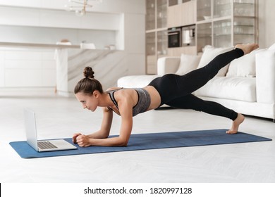 Athletic Beautiful Woman Training At Home In Her Apartment, Doing Plank Exercise With Online Tutorial, Watching Virtual Fitness Workout Class On Laptop. Sport, Wellness And Health Lifestyle Concept