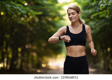 Athletic blonde woman looking at fitness bracelet while running alone outdoors, smiling middle aged woman in sportswear checking tracker on her wrist, exercising at public park, copy space - Powered by Shutterstock