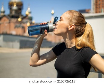 Athletic Blonde Woman In Sportswear Drinking A Protein Shake Or A Bottle Of Water After A Workout Outdoors. The Concept Of Sports And Recreation.