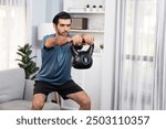 Athletic body and active sporty man doing squat with kettlebell weight for effective targeting muscle gain at gaiety home as concept of healthy fit body home workout lifestyle.