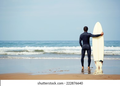 Athletic build young surfer holding surfboard while standing on the beach looking at ocean to find the perfect spot to go surfing waves, professional surfer waiting waves on the ocean beach - Powered by Shutterstock