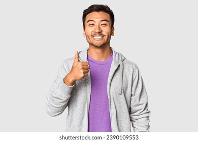 Athletic Chinese man in sportswear in studio smiling and raising thumb up - Powered by Shutterstock