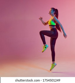 Athletic Cool Girl Trainer Teaches And Work Out Online Training On A Bright Neon Background.