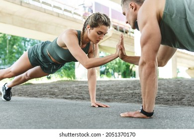 Athletic couple and fitness training outdoors. Man and woman doing push-ups exercise for chest and triceps muscles during street workout 