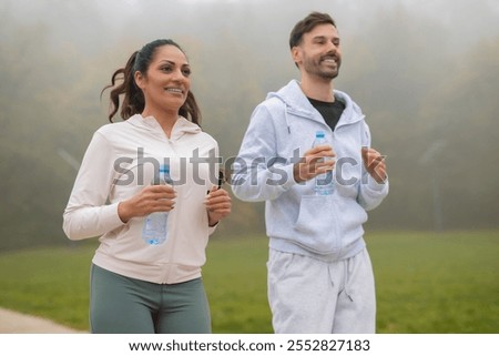 athletic couple jogging while exercising in nature. focus is on woman