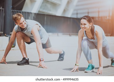 Athletic couple in sprint start position preparing for a run.