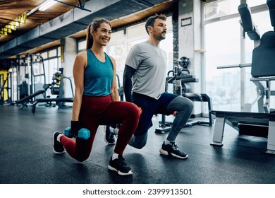 Athletic couple using dumbbells while exercising in lunge position in a gym. Copy space. - Powered by Shutterstock