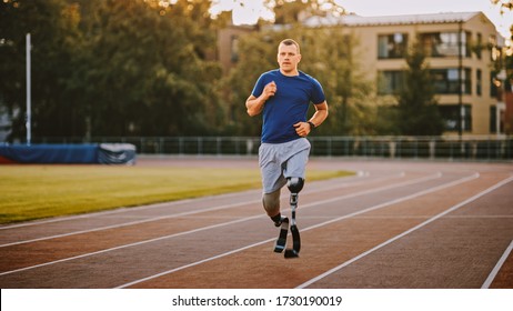 Athletic Disabled Fit Man with Prosthetic Running Blades is Training on a Outdoors Stadium on a Sunny Afternoon. Amputee Runner Jogging on a Stadium Track. Motivational Sports Shot.