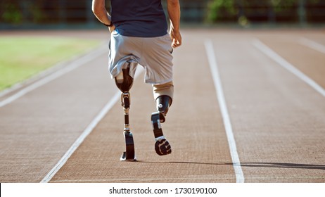 Athletic Disabled Fit Man with Prosthetic Running Blades is Training on Outdoors Stadium on Sunny Afternoon. Amputee Runner Jogging on a Stadium Track. Motivational Sports Shot. Leg Shot.