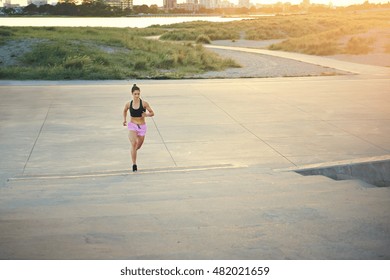 Athletic Female Long Distance Runner Out Jogging Along A Country Road At Dawn With A Golden Glow From The Rising Sun