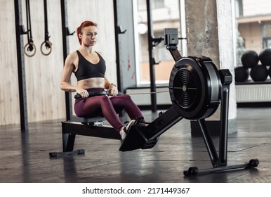 Athletic Fines Woman Exercising With Rowing Exercise Machine In Modern Gym