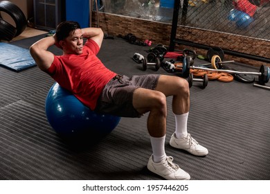 An Athletic And Fit Asian Man Does Stability Ball Crunches. Abs And Core Workout.