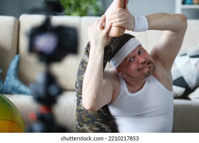 Athletic Funny Man Warming Up, Stretching His Legs And Watching Or Filming Fitness Video Lesson Online