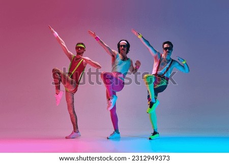Athletic, funny men in retro colorful sportswear training, doing exercises against gradient blue pink studio background in neon light. Concept of sportive and active lifestyle, humor, retro style. Ad