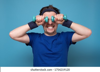 Athletic funny young man doing exercise dumbbell. Studio shot