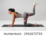 Athletic girl doing kickback exercise for glutes with resistance band. Fitness woman working out donkey kicks
