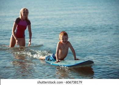 Athletic Girl With Little Boy Teaching Him Surfing